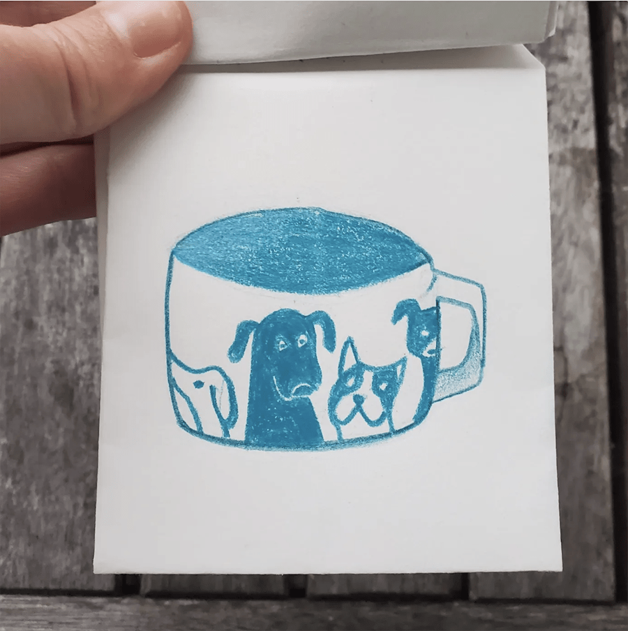 The first page of the small booklet. It shows a drawing of a mug with dogs on it.