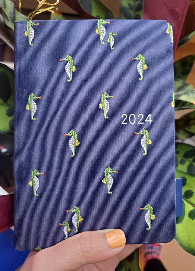 A small notebook with a fabric cover with a pattern of green sea horses
