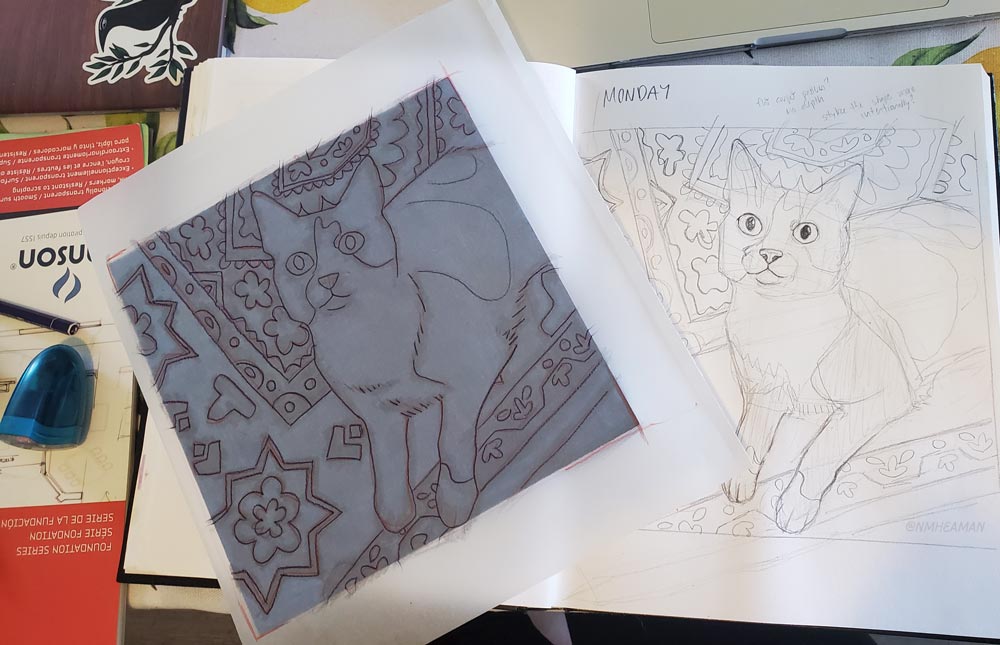 A photo showing the original sketch of Monday, and a copy on tracing paper, which is being used to transfer the drawing onto a wood panel. 
